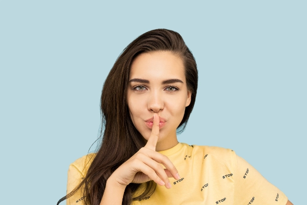 Une fille suggérant la discrétion en ayant un doig posé sur la bouche